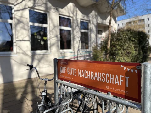 Auf einem Schild steht der Spruch Auf Gute Nachbarschaft im Benn Wartenberg.