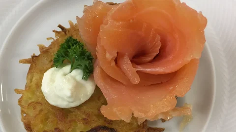 Häppchen aus Lachs und Kartoffelpuffer mit Soße angerichtet