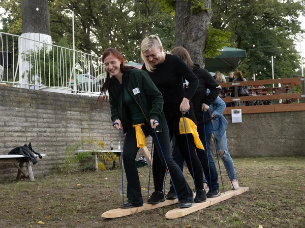 Vier Frauen stehen hintereinander auf zwei langen Holzbrettern und halten Seile zum Balancieren