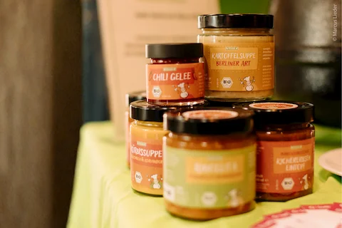 Auf einem Tisch stehen fünf SozDia Suppen im Glas zu einer Pyramide gestapelt.