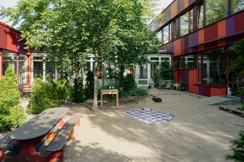 Der freundliche Innenhof mit Sand und viel Grün lädt zum Spielen ein