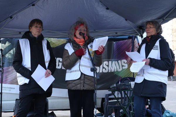 Drei Frauen von 'Omas gegen Rechts' bei einer Demonstration gegen Rassismus, eine spricht ins Mikrofon.