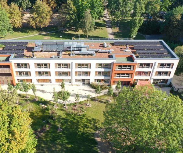 Ein großes Gebäude von oben fotografiert. Das Gebäude ist umgeben von einem grünen Garten.