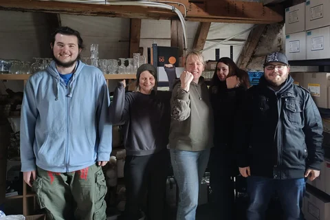 Fünf Personen lachen ins Foto und zeigen das sie zusammen etwas geschafft haben