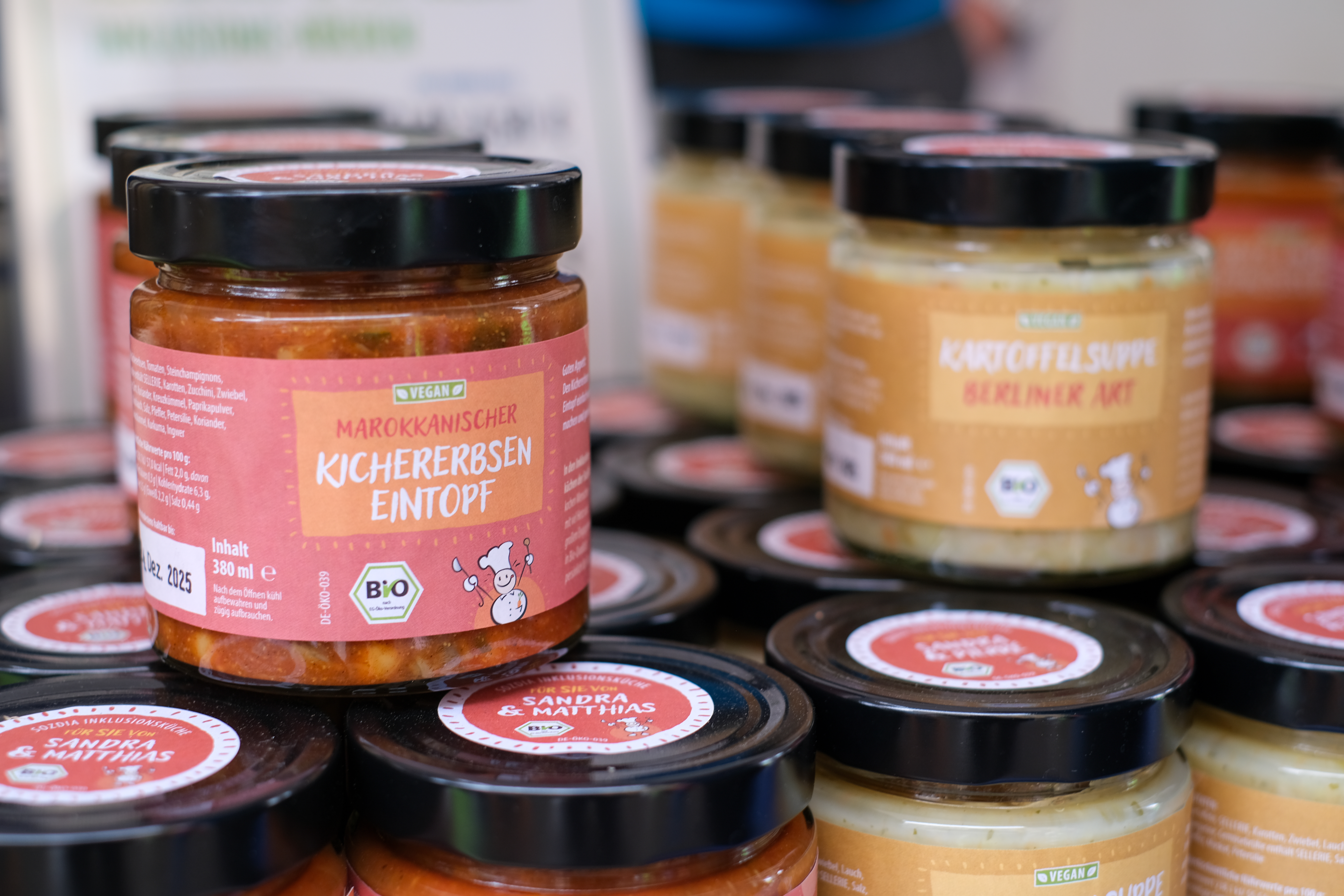 Nahaufnahme von Gläsern mit veganem marokkanischem Kichererbseneintopf und Kartoffelsuppe Berliner Art von Sozia Inklusionsküche.