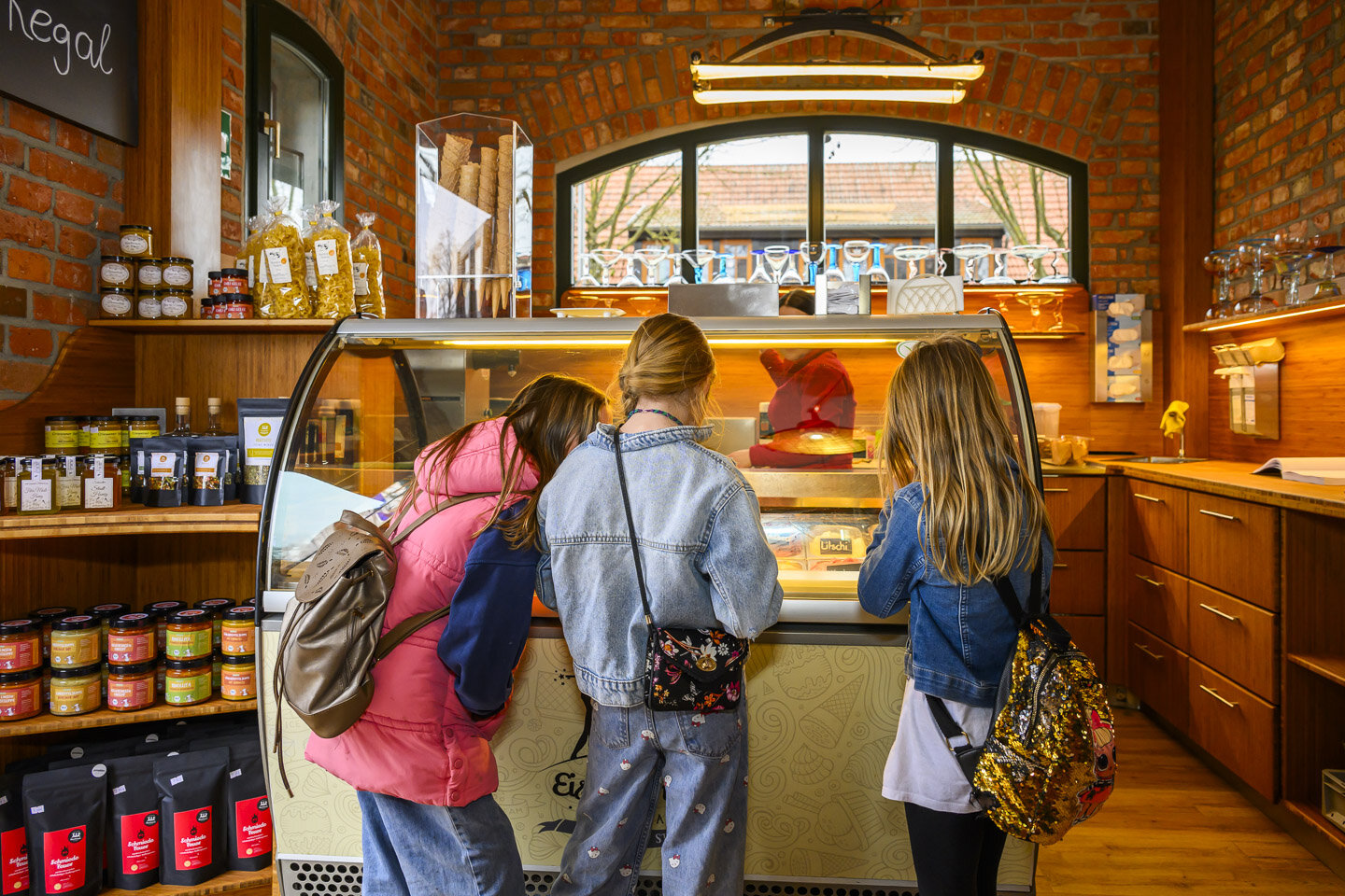Mehrere Kinder stehen vor der Eisvitrine der Eisschmiede Uckermark und wollen Eis kaufen. 