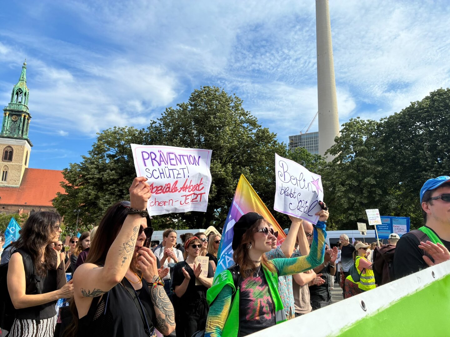 Menschenmenge bei Demonstration mit Schildern, im Hintergrund Fernsehturm und Kirchturm