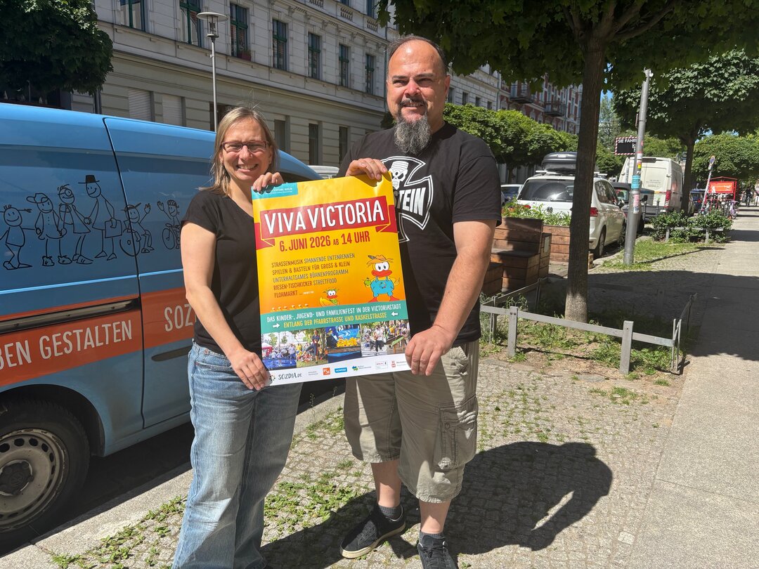 Die beiden für das Viva verantwortlichen SozDia-Mitarbeitenden mit einem Werbposter für das Viva Victoria.